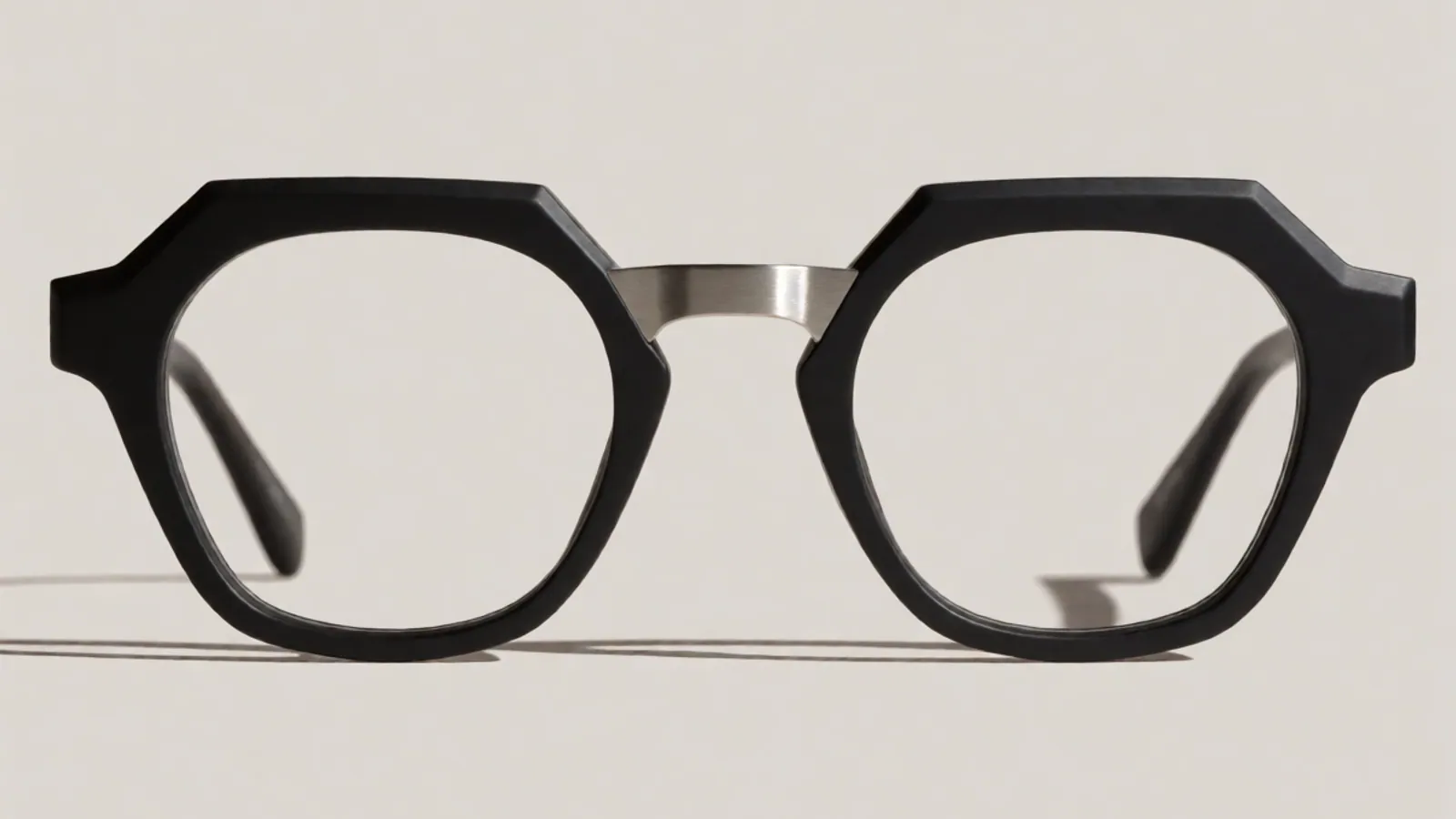 The front of the matte black and steel combination geometric frame, photographed straight on against pale grey stone.