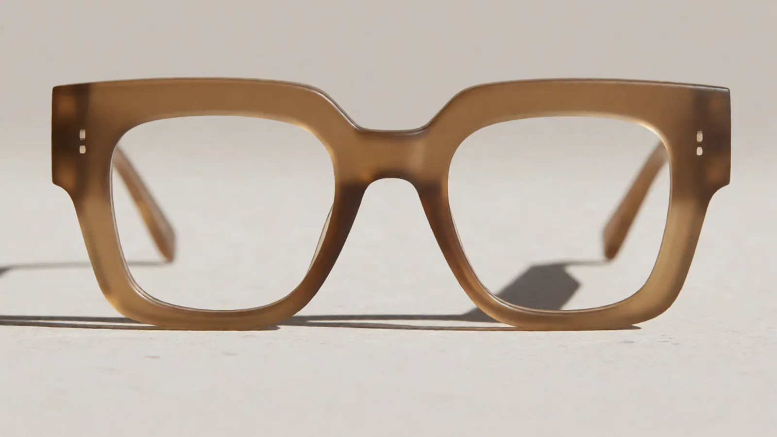 The front of the sand acetate square frame, photographed straight on against pale grey stone.