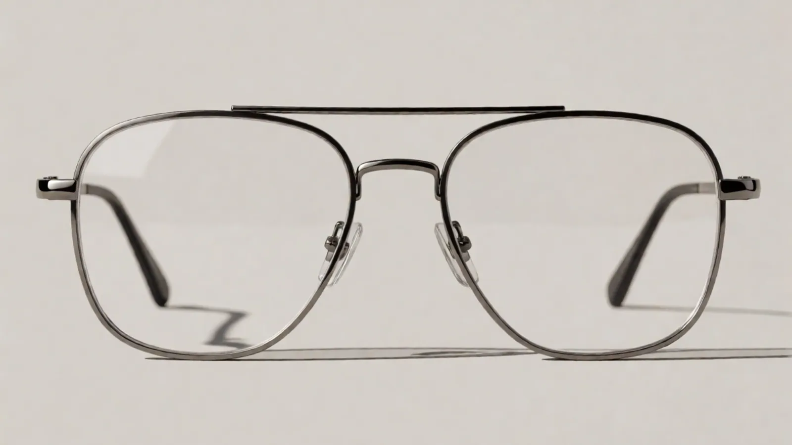 The front of the gunmetal stainless steel aviator frame, photographed straight on against pale grey stone.
