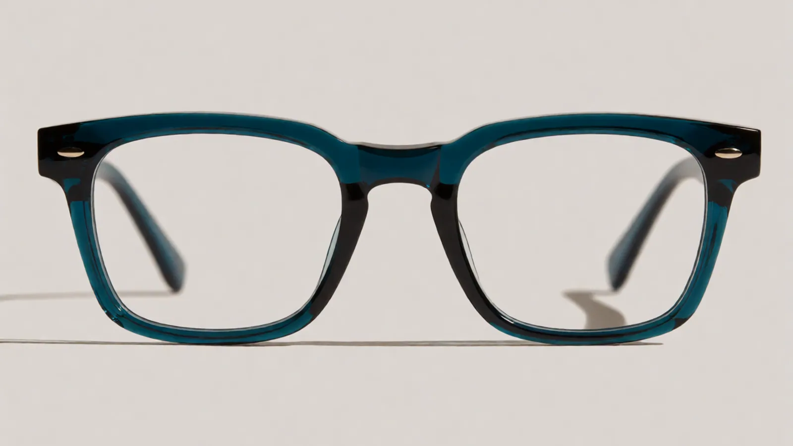 The front of the deep teal acetate rectangle frame, photographed straight on against pale grey stone.