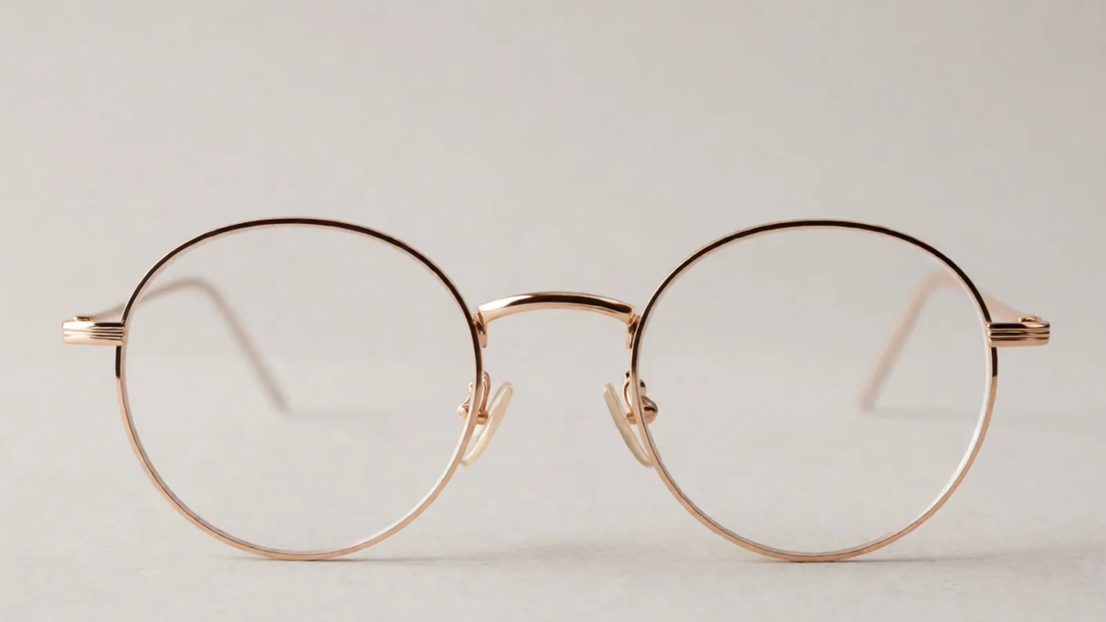 The front of the rose gold titanium round frame, photographed straight on against pale grey stone.
