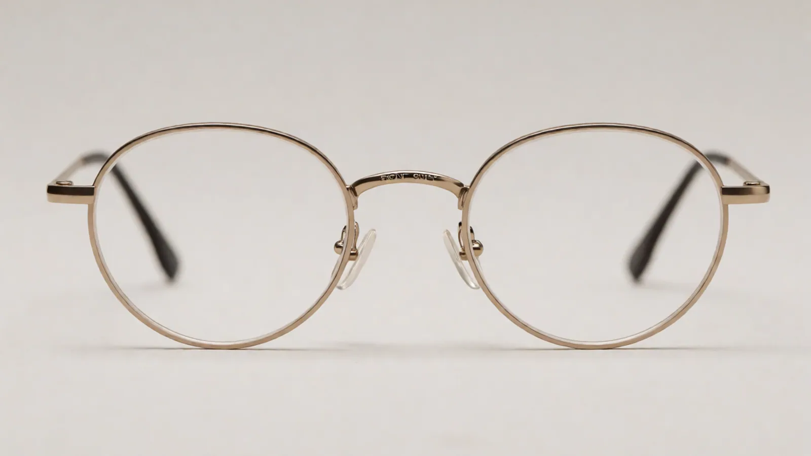 The front of the champagne titanium oval frame, photographed straight on against pale grey stone.