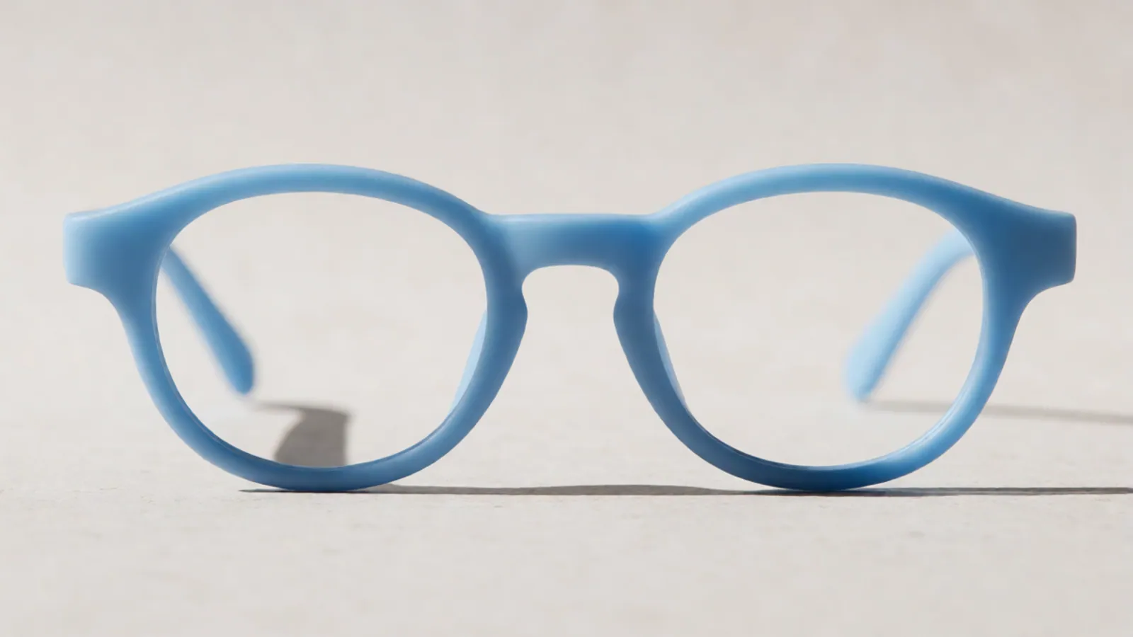 The front of the sky blue flexible nylon oval frame, photographed straight on against pale grey stone.