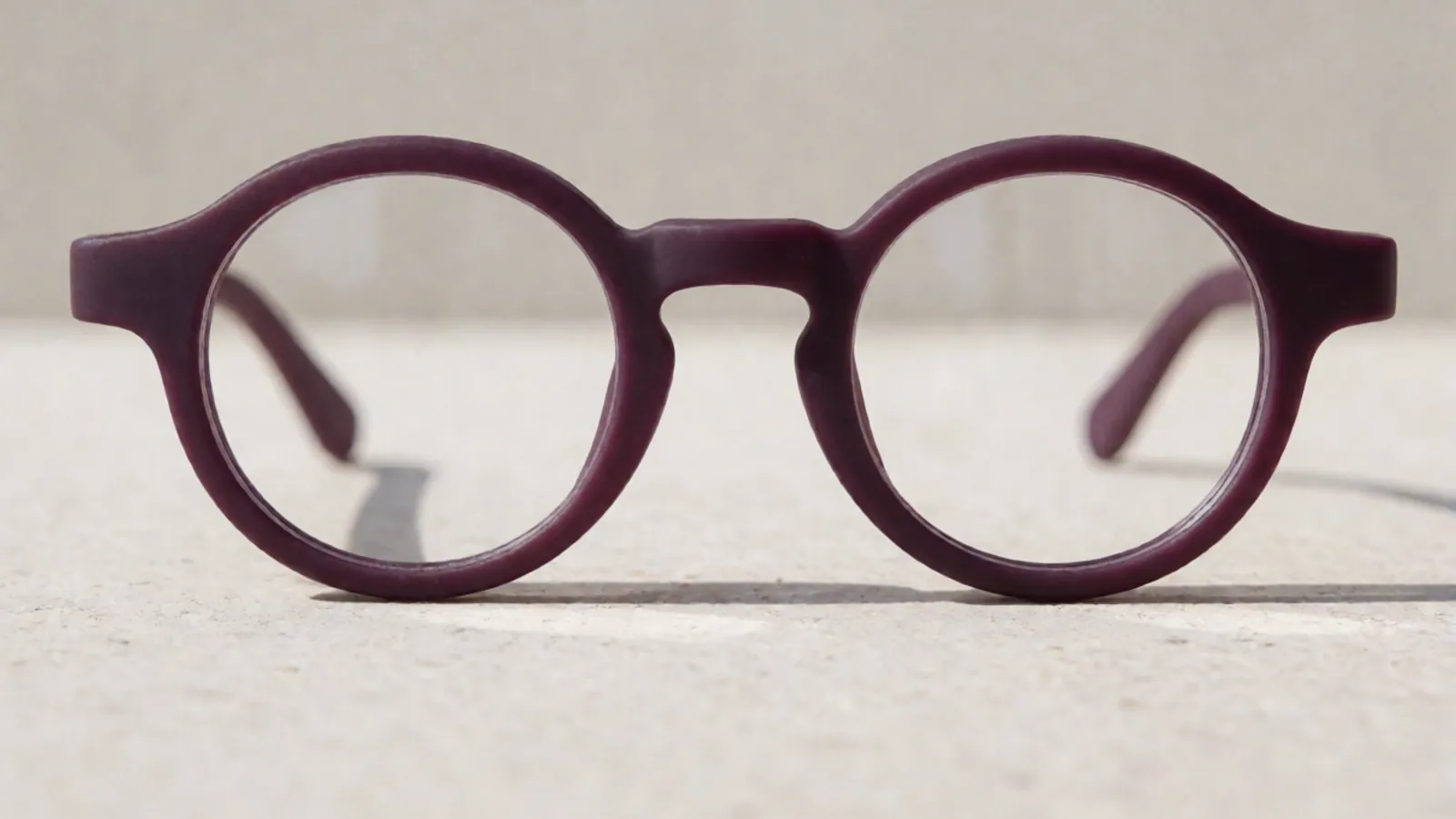 The front of the plum flexible nylon round frame, photographed straight on against pale grey stone.