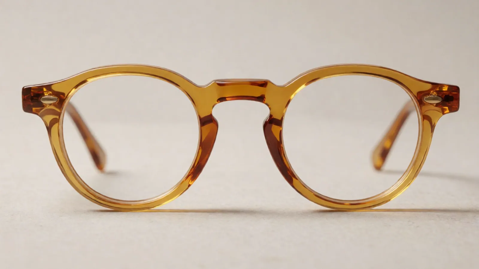 The front of the crystal amber acetate round frame, photographed straight on against pale grey stone.